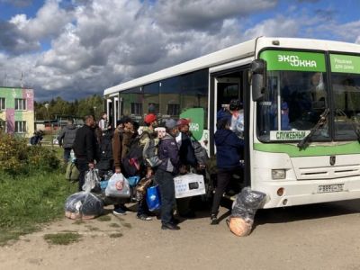 Группа рабочих мигрантов предприятия "Экоокна" садится в автобус, чтобы покинуть Бужаниново, где накануне прошел народны сход. Фото: "Би-би-си"